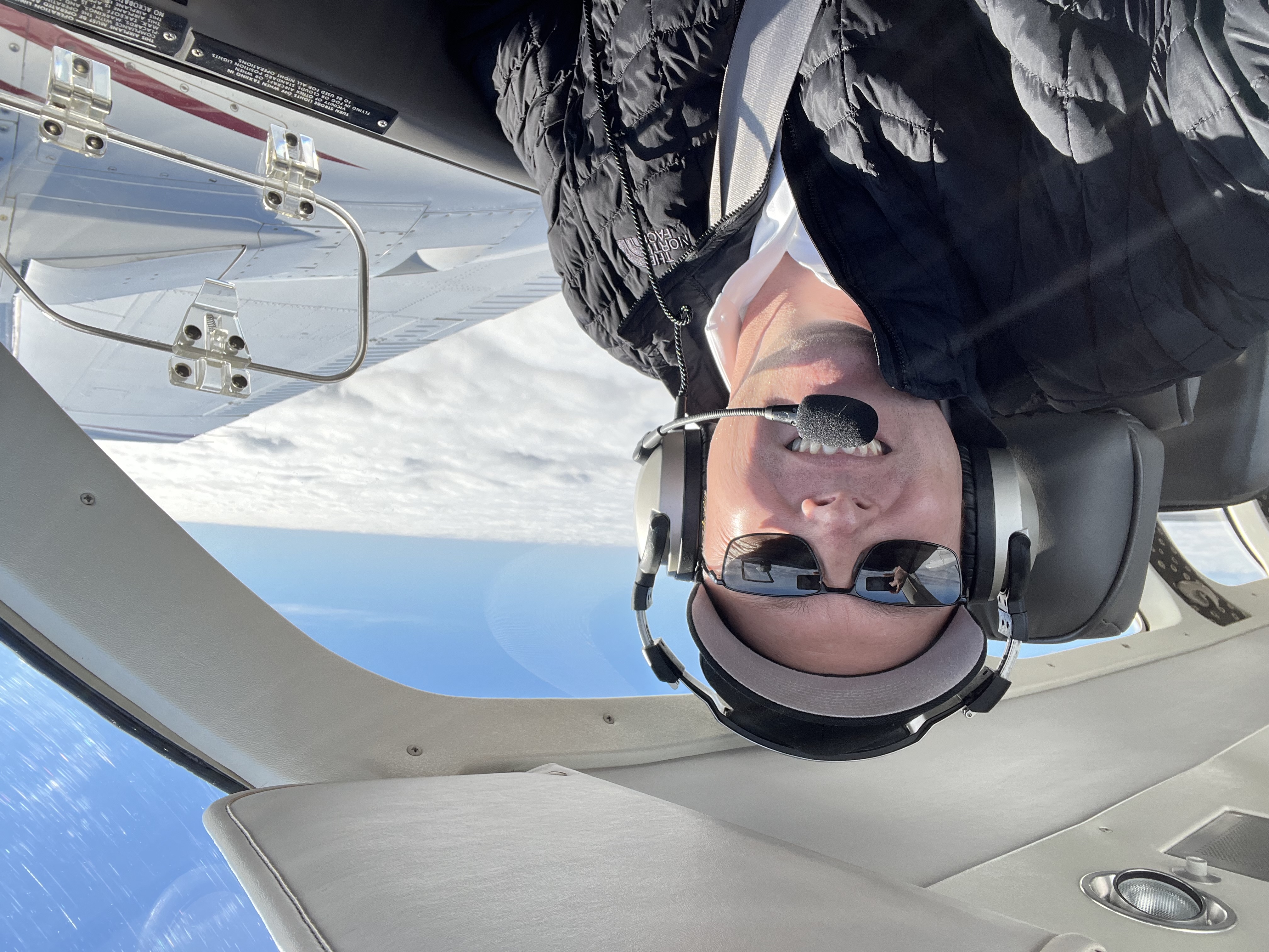Travis Alkire flying above the clouds in a small aircraft